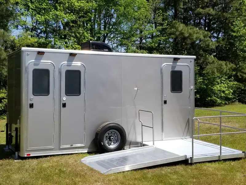 Silver ADA restroom trailer with three doors and a wheelchair ramp