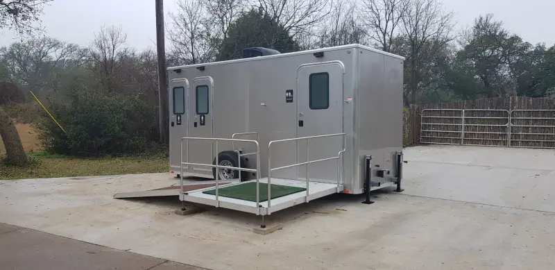 ADA restroom trailer with a turf-covered ramp landing and railings
