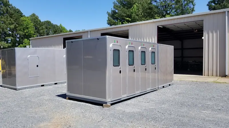 Several restroom skids staged outside a shop building