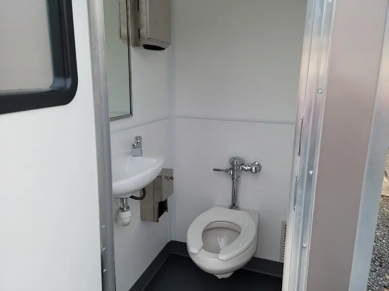 ADA restroom interior with a toilet, wall-mounted sink and mirror