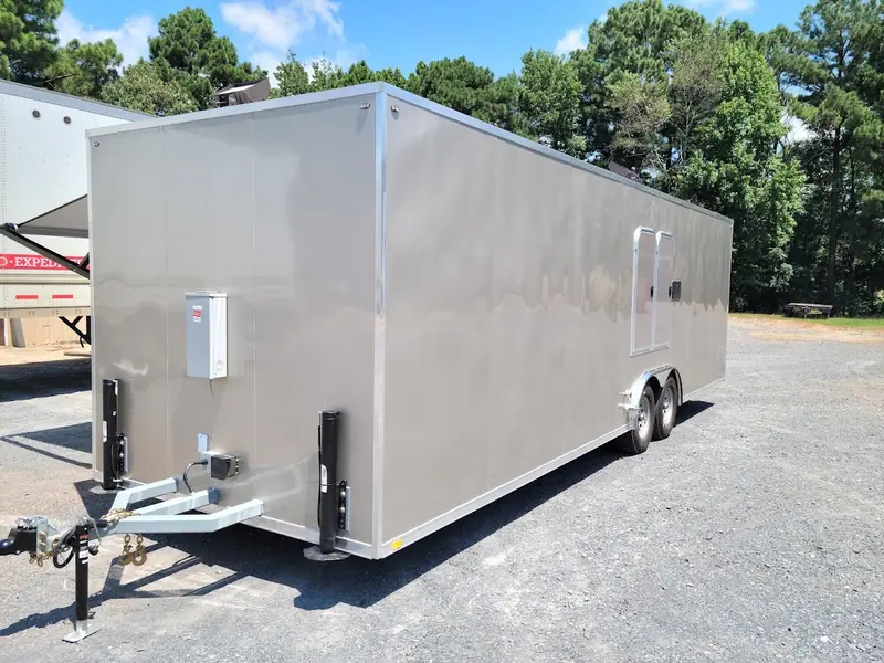 Dual-axle enclosed restroom trailer parked on gravel
