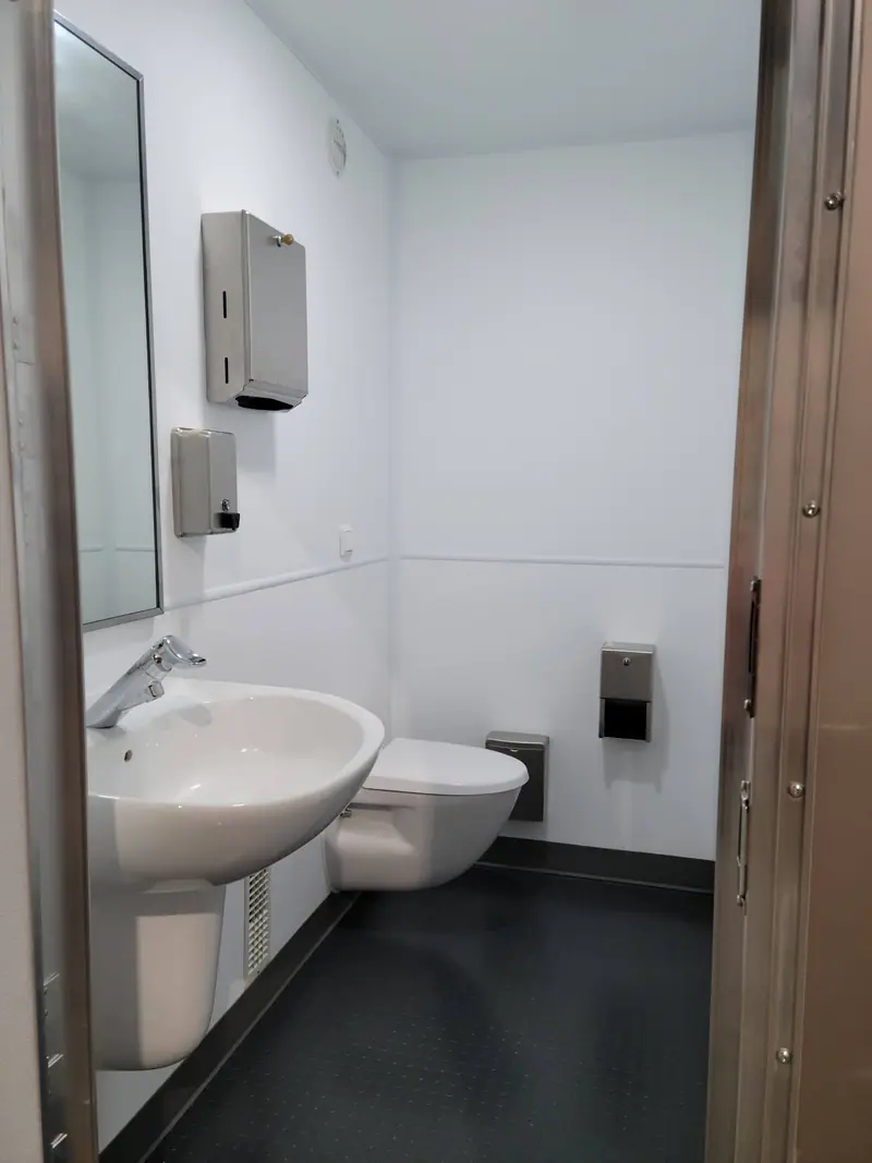Restroom inside an off grid Comfort Isle skid with a wall-hung toilet and sink