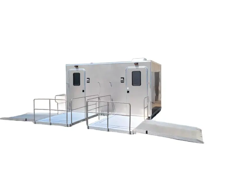 The CI 14 - 2 Stall ADA Restroom Skid (14 ft) is a silver trailer featuring two doors, metal handrails, and accessible ramps on both sides, shown isolated against a white background.