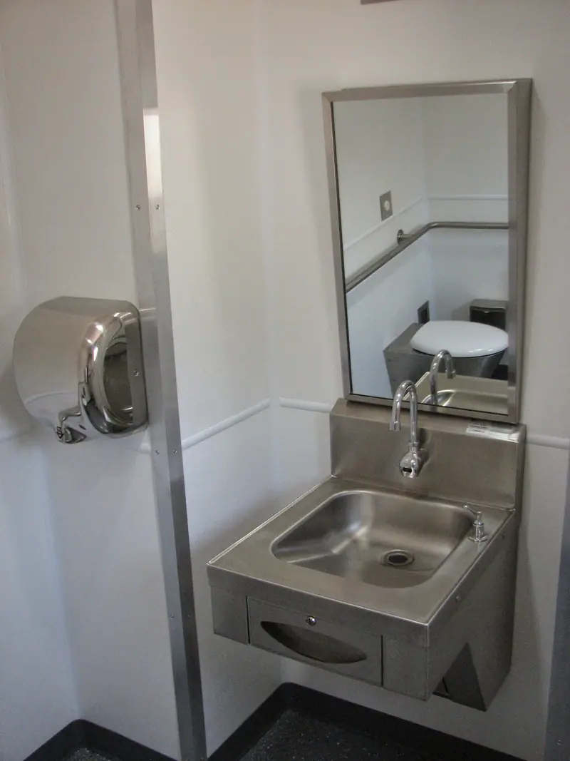 Stainless steel sink and mirror inside a restroom unit