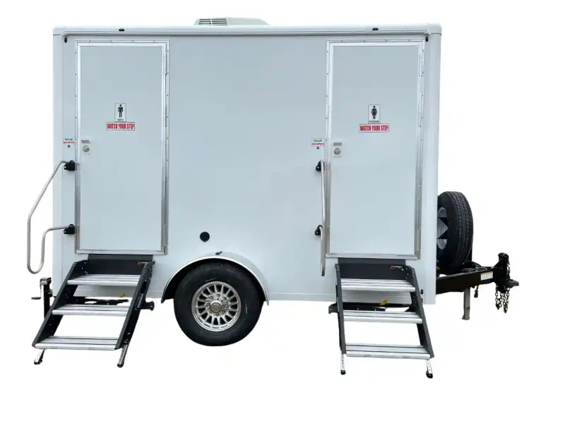 The OI-212 — 2 Person Stall Restroom Trailer (12' x 6') features two separate doors with metal steps and a front-right spare tire. This portable unit offers convenient ADA restroom facilities for events or job sites.