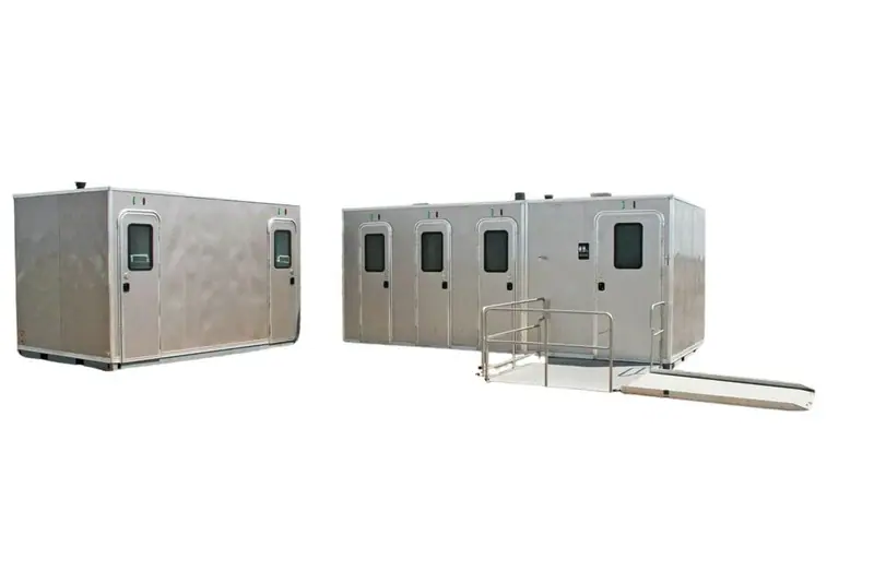 The CI 8 - 1 Stall ADA Restroom Skid (8 ft), a metallic portable unit with an attached ADA ramp, stands isolated on a white background.